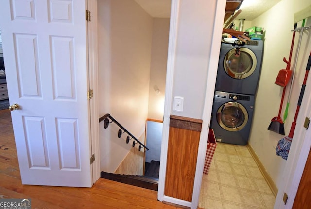 laundry room featuring tile patterned floors, laundry area, stacked washer / drying machine, and baseboards