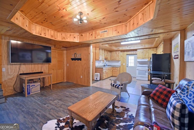 living room featuring visible vents, a tray ceiling, wood finished floors, wood walls, and wood ceiling