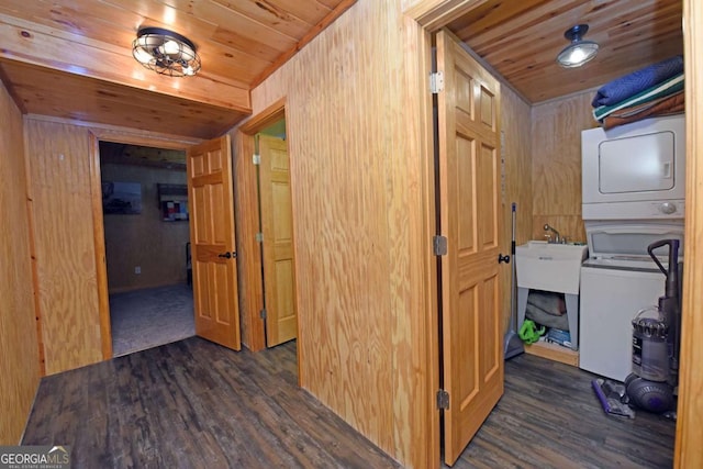 hallway with dark wood finished floors, wooden ceiling, stacked washer / drying machine, and a sink