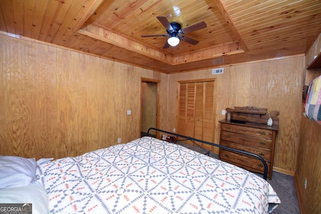 bedroom with visible vents, a tray ceiling, wood walls, wooden ceiling, and carpet flooring