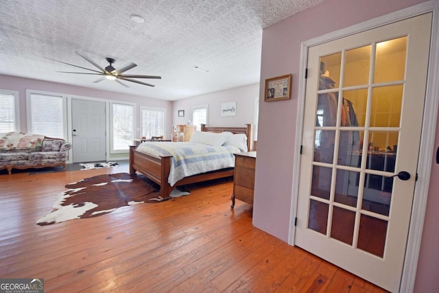 bedroom with hardwood / wood-style floors, a ceiling fan, and a textured ceiling