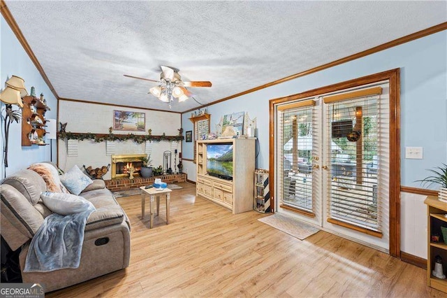 living room featuring light wood-style floors, ceiling fan, crown molding, and a textured ceiling