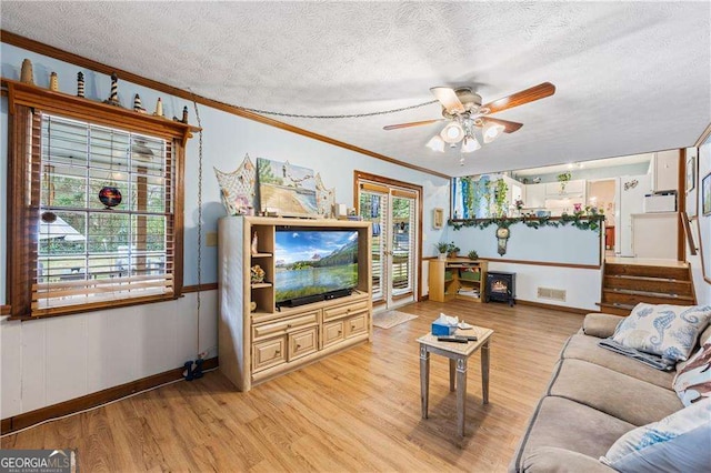 living room featuring visible vents, ornamental molding, a ceiling fan, a textured ceiling, and light wood-style floors