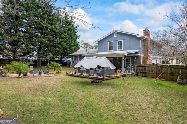 rear view of house with a wooden deck, a lawn, a fenced backyard, and a chimney