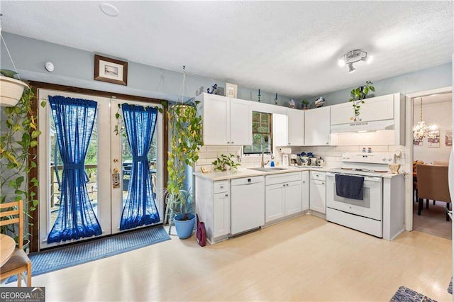 kitchen featuring white appliances, a sink, decorative backsplash, light countertops, and white cabinets