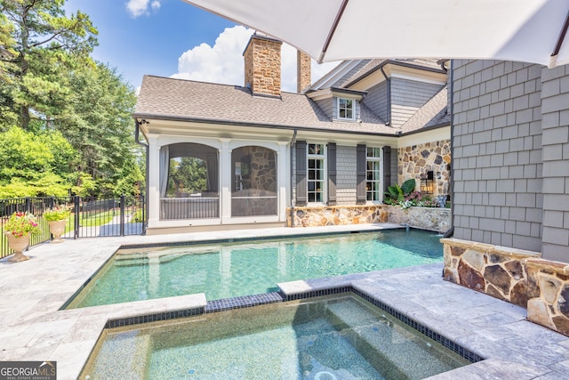 view of swimming pool featuring a patio area, a pool with connected hot tub, and fence