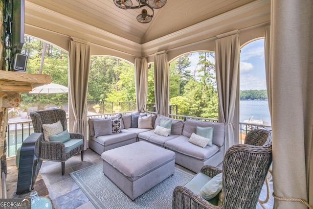 sunroom with stone tile floors, wooden ceiling, a water view, and lofted ceiling