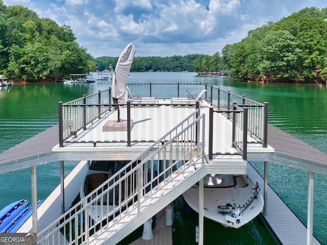 dock area with a wooded view, a water view, and stairs