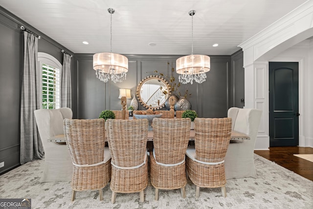 dining space featuring a decorative wall, wood finished floors, and a chandelier