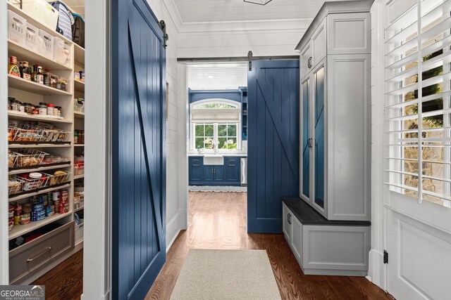 mudroom with a barn door and dark wood finished floors