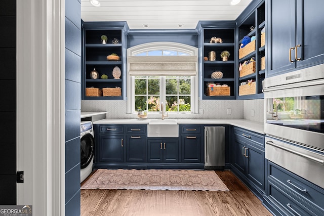 interior space with dark wood finished floors, washer / clothes dryer, laundry area, and a sink