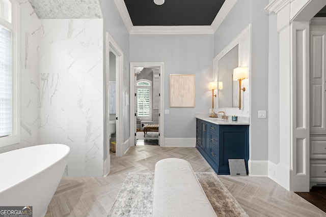 bathroom with a freestanding tub, vanity, crown molding, and baseboards