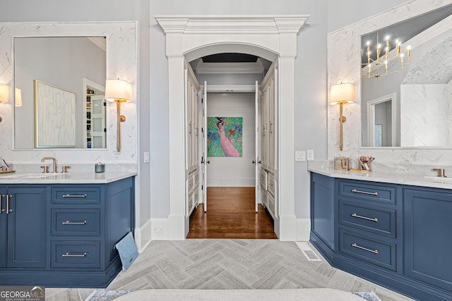 bathroom with baseboards, two vanities, crown molding, and a sink