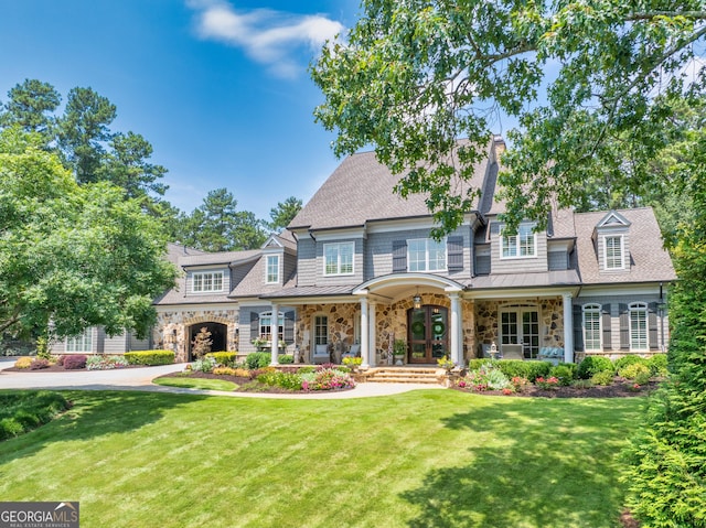 view of front of home featuring a porch, a front lawn, a standing seam roof, a shingled roof, and stone siding