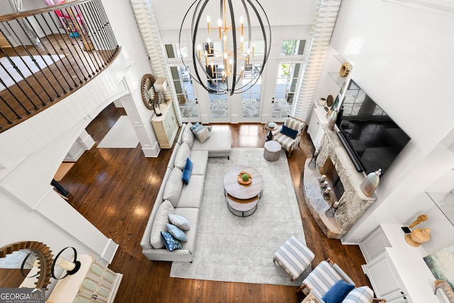 living area with wood finished floors, a fireplace with raised hearth, and a chandelier
