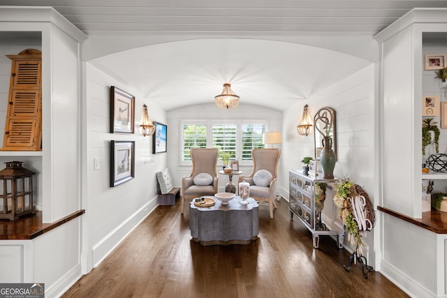 living area with wood finished floors, a notable chandelier, vaulted ceiling, and baseboards