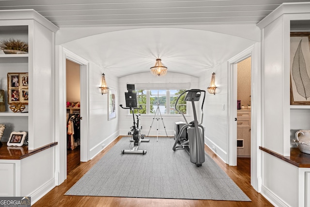 workout room with lofted ceiling, wood finished floors, arched walkways, and baseboards