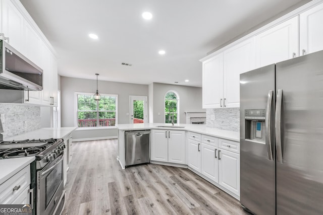 kitchen featuring light wood finished floors, appliances with stainless steel finishes, light countertops, and a peninsula