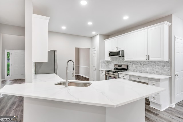 kitchen with a sink, decorative backsplash, white cabinets, and stainless steel appliances