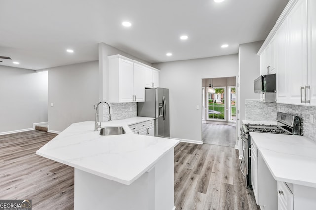 kitchen featuring a peninsula, a sink, stainless steel appliances, white cabinetry, and backsplash