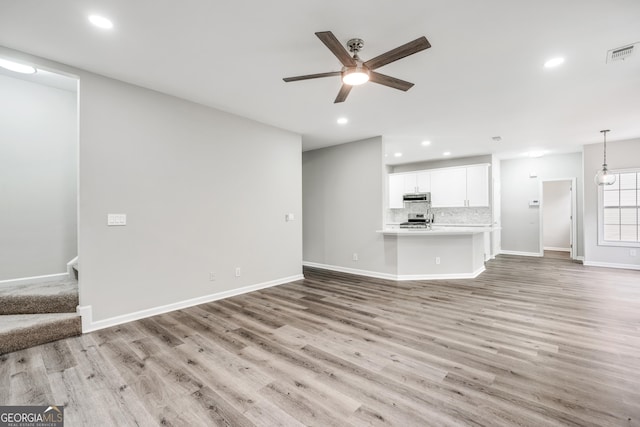 unfurnished living room featuring stairway, recessed lighting, visible vents, and light wood-type flooring