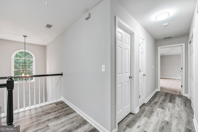 hallway with visible vents, baseboards, and wood finished floors