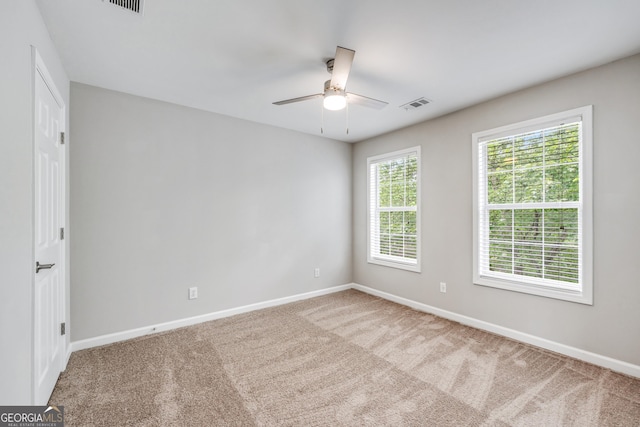 carpeted empty room with baseboards, visible vents, and ceiling fan