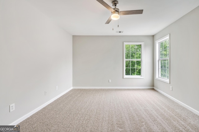 carpeted empty room with baseboards, visible vents, and ceiling fan