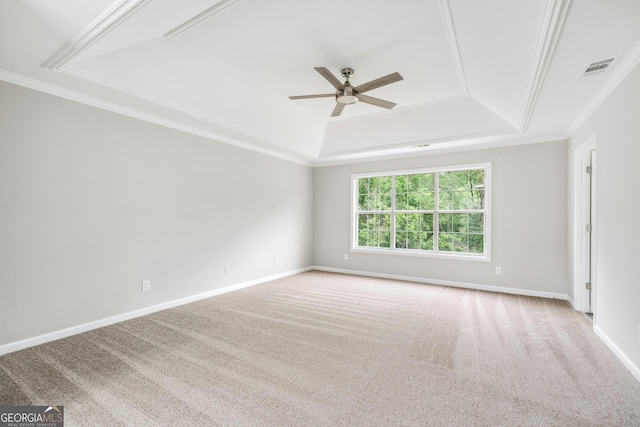 carpeted spare room with a ceiling fan, visible vents, baseboards, a tray ceiling, and crown molding