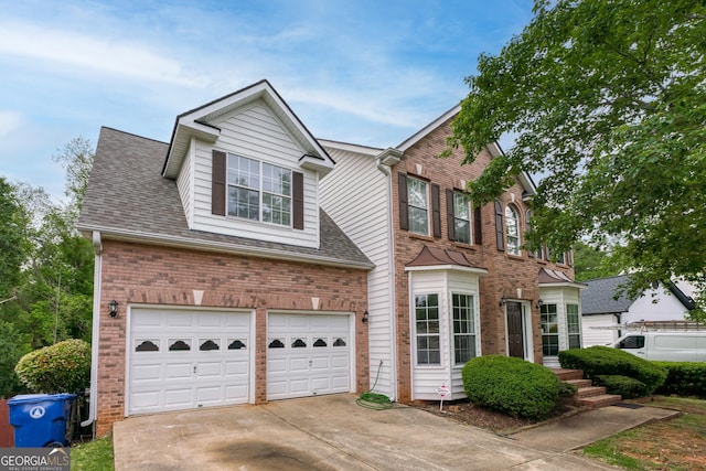 colonial inspired home featuring brick siding, a garage, concrete driveway, and roof with shingles