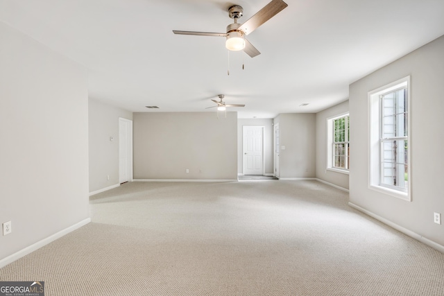 empty room with carpet flooring, a ceiling fan, and baseboards