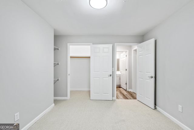 unfurnished bedroom featuring a spacious closet, a closet, baseboards, and carpet floors