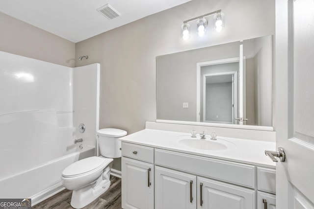 bathroom featuring vanity, wood finished floors, visible vents, shower / washtub combination, and toilet