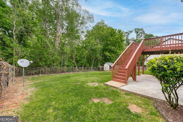 view of yard featuring a patio area, a deck, stairs, and fence