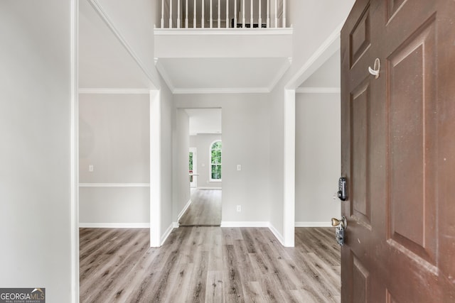 foyer entrance with baseboards, wood finished floors, and ornamental molding