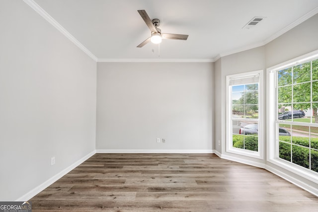 unfurnished room with visible vents, baseboards, wood finished floors, and ornamental molding