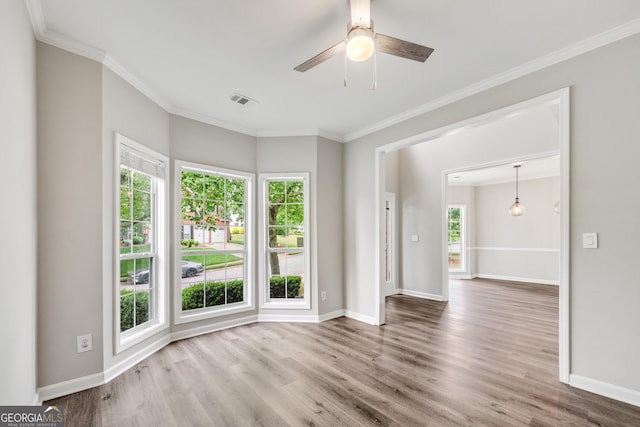 spare room with visible vents, plenty of natural light, ornamental molding, and wood finished floors