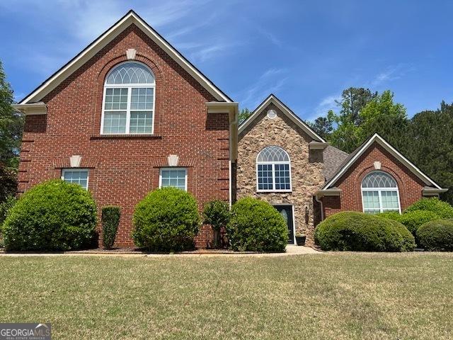traditional-style house featuring stone siding and a front lawn