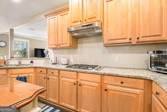 kitchen with crown molding, a sink, stainless steel gas stovetop, backsplash, and under cabinet range hood