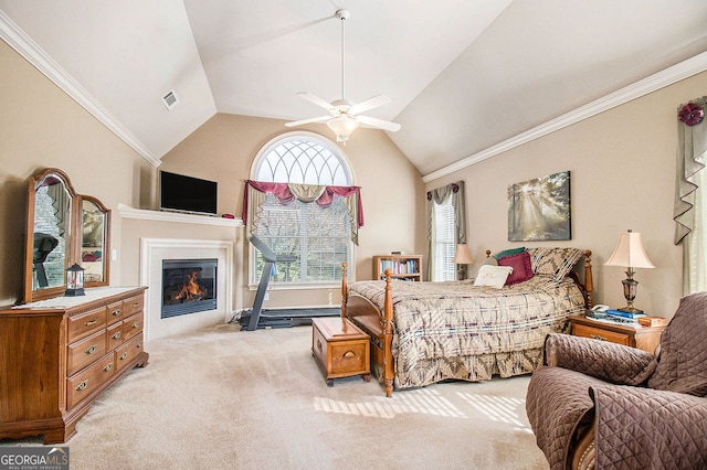 bedroom with a ceiling fan, vaulted ceiling, light carpet, a glass covered fireplace, and crown molding