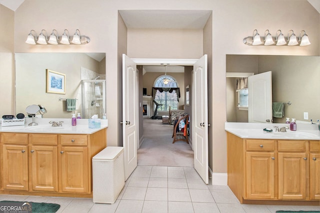 full bathroom with a sink, a stall shower, ensuite bath, tile patterned flooring, and two vanities