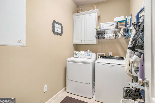 washroom with washing machine and clothes dryer, cabinet space, baseboards, and light tile patterned flooring