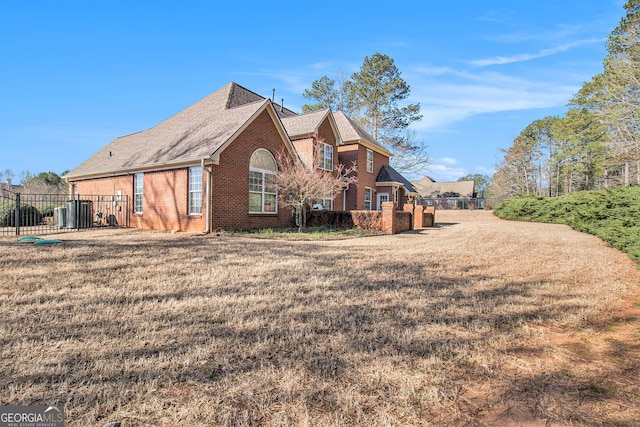 rear view of property featuring a yard, fence, and brick siding