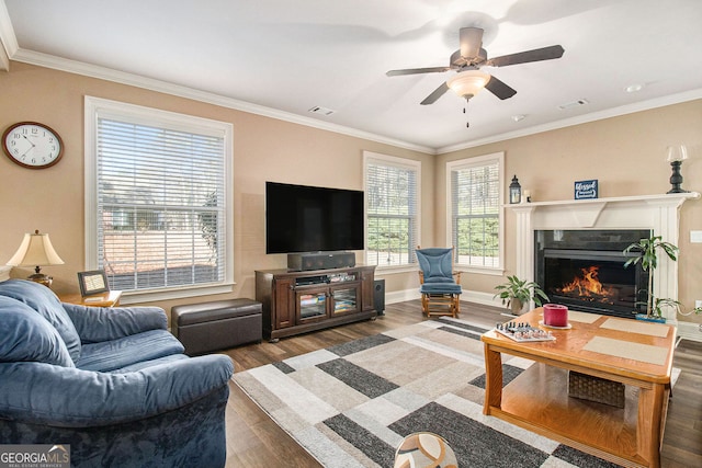 living area featuring a high end fireplace, ceiling fan, baseboards, ornamental molding, and wood finished floors