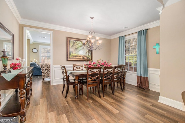 dining room featuring wood finished floors, wainscoting, and ornamental molding