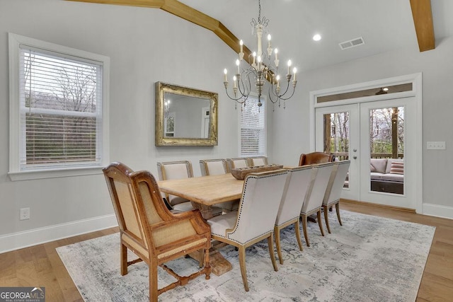 dining area featuring visible vents, a healthy amount of sunlight, wood finished floors, and vaulted ceiling