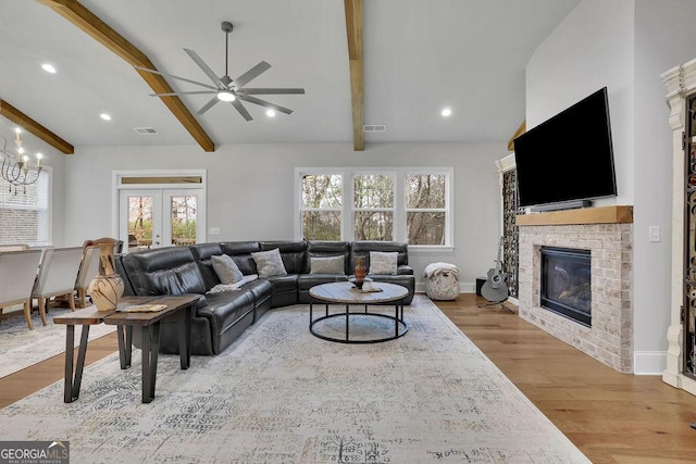 living room featuring a brick fireplace, beamed ceiling, french doors, and visible vents