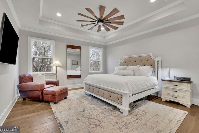 bedroom featuring a raised ceiling, hardwood / wood-style flooring, and multiple windows