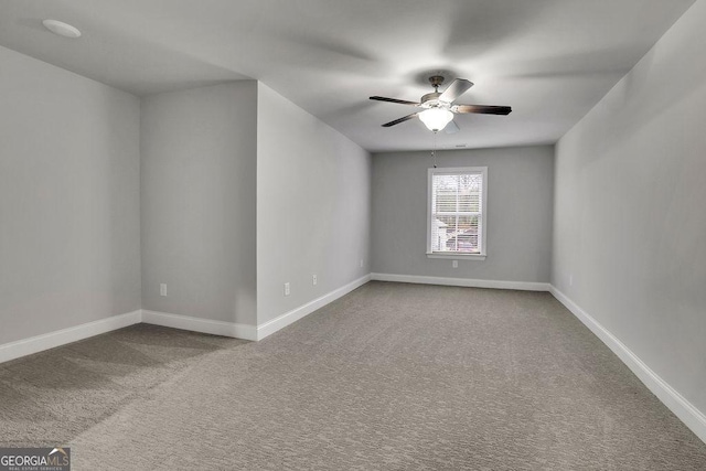 carpeted spare room featuring baseboards and a ceiling fan