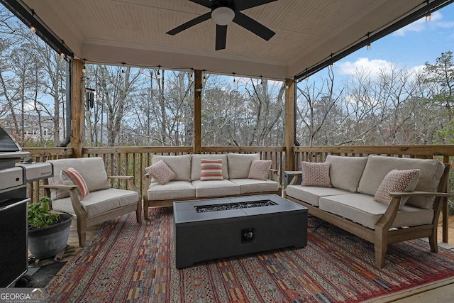 deck with grilling area, an outdoor living space with a fire pit, and a ceiling fan